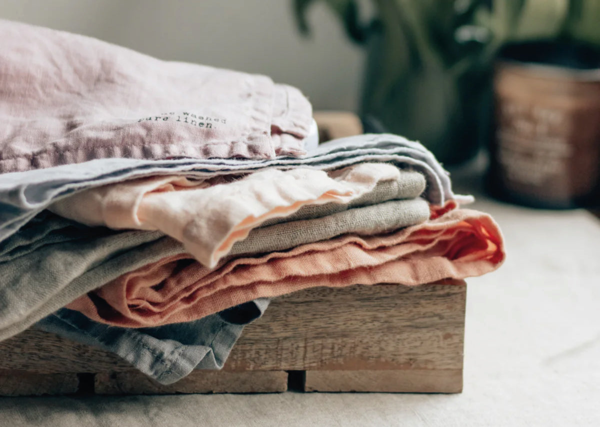 A pile of linen clothes sit on a table.