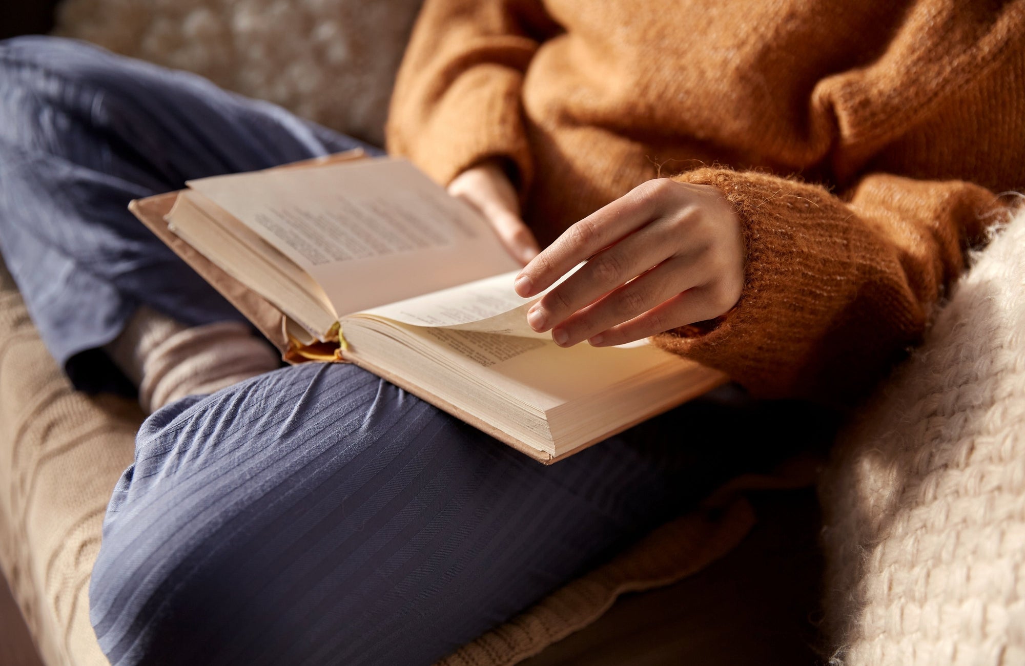 A woman reads a book on the couch