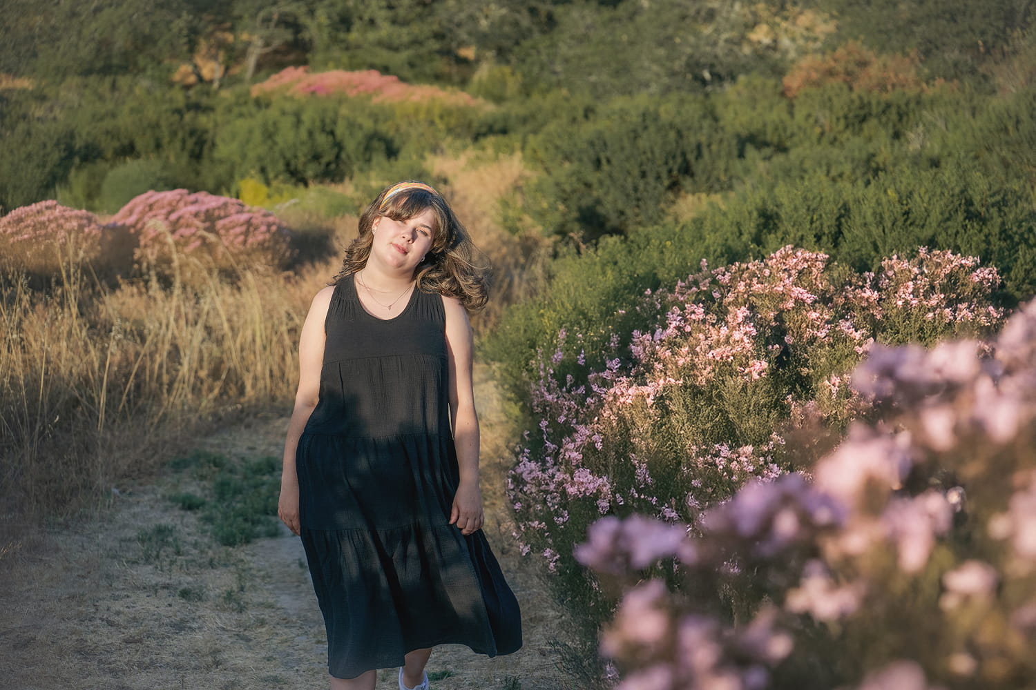 A woman walks in the wildflowers wearing a Teresa Dress