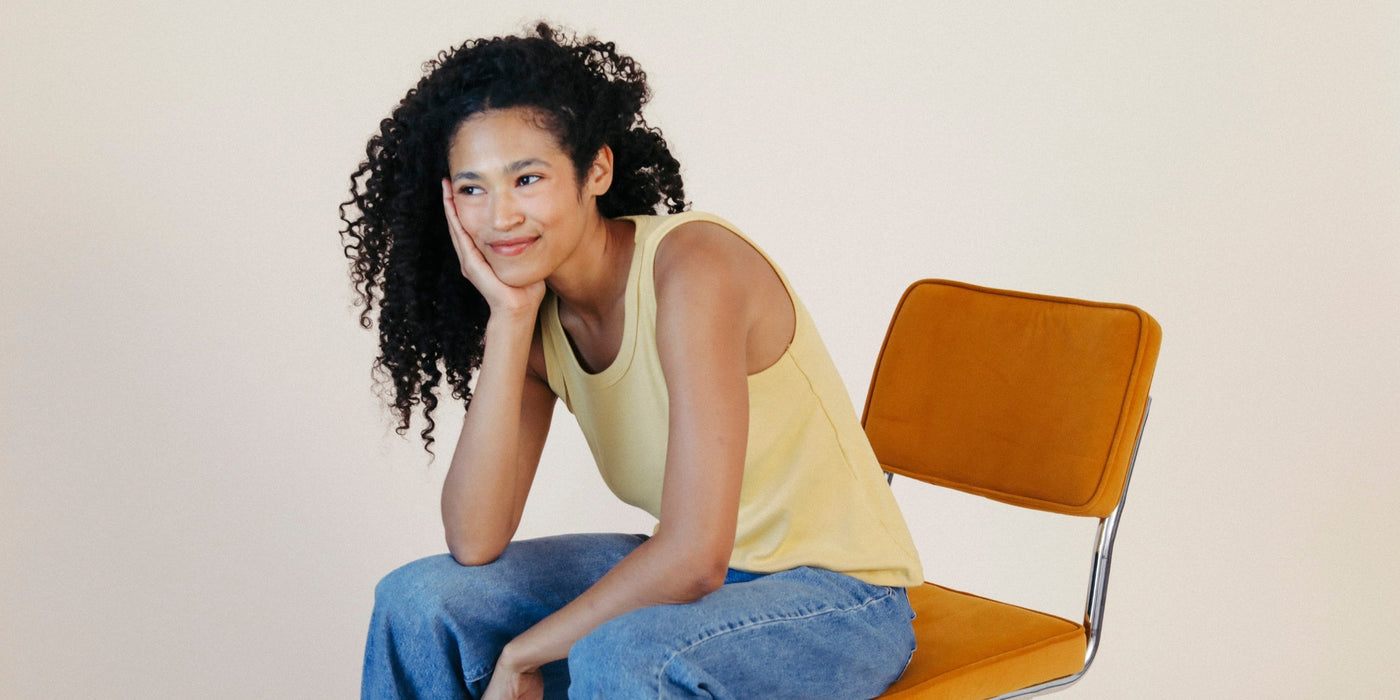 A woman smiles sitting on a chair