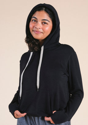 Person wearing a black hoodie with a beige background