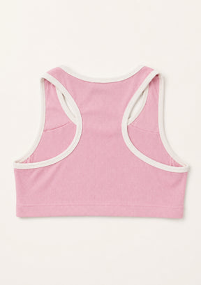 A pink cropped tank top shown from the back, featuring contrasting white trim along the racerback straps and neckline, laid flat against a light cream background.