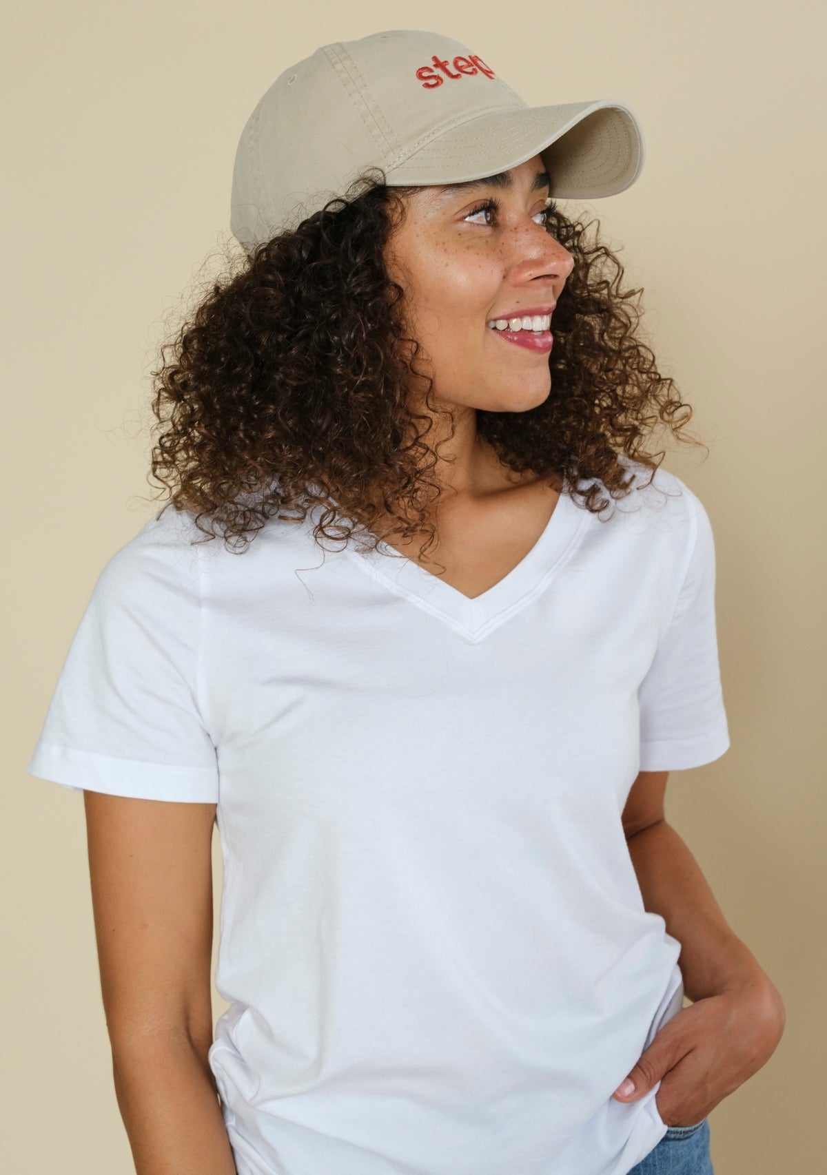 Side profile of cream unstructured baseball cap with curved brim and casual everyday fit