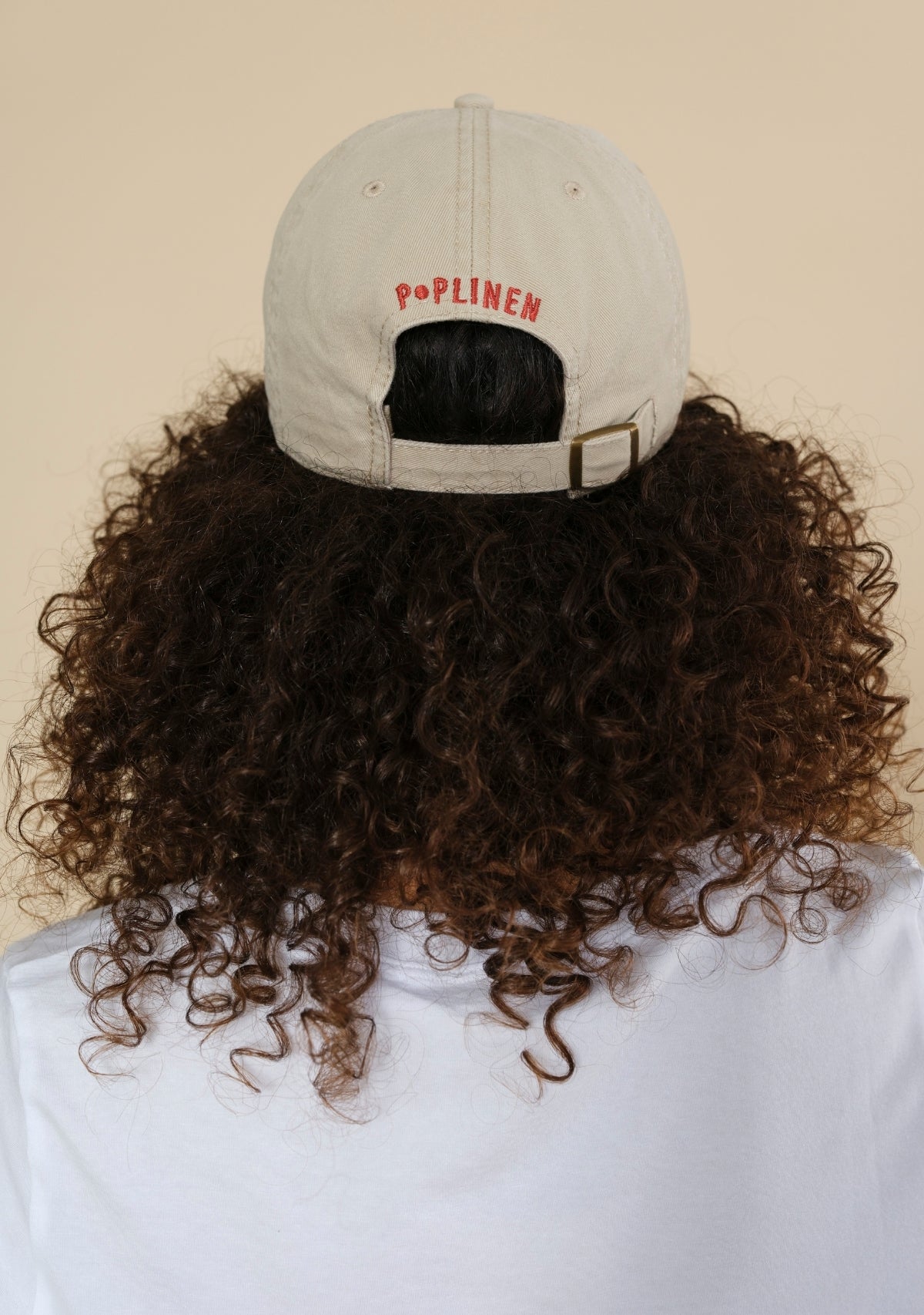 Back of cream Step Up baseball cap with Poplinen logo and adjustable snap-button strap