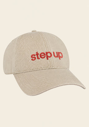 Close-up of Step Up logo embroidery on beige baseball cap