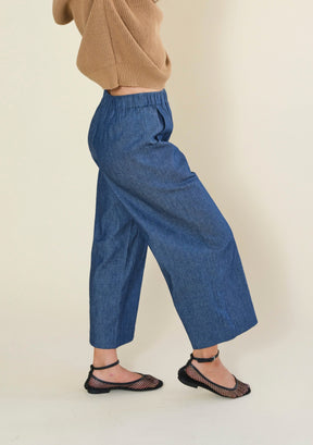 Side profile of women's blue denim wide leg pants with relaxed silhouette and cropped hem