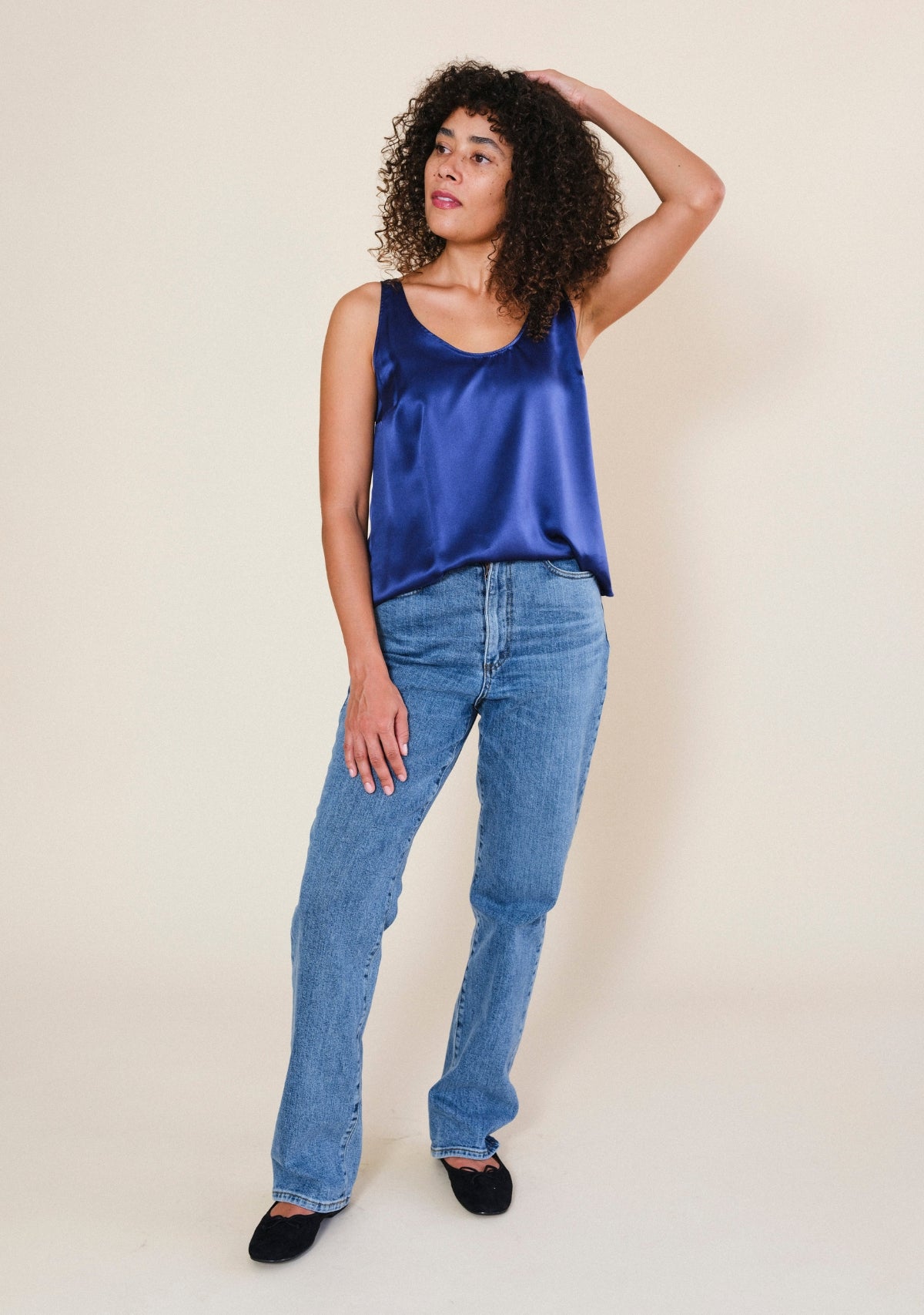 Woman styling navy silk tank top with casual everyday layers