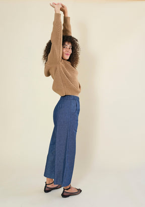 Side profile of women's blue denim wide leg pants with relaxed silhouette and cropped hem