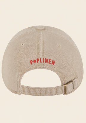Adjustable snap-button closure on cream baseball cap with opening for ponytail