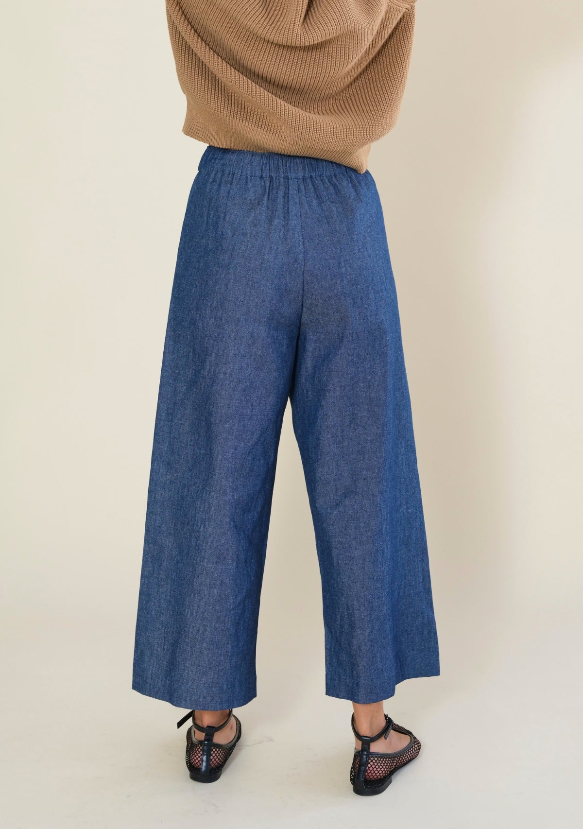 Back view of Poplinen Nin blue denim cropped wide leg pants with comfortable elastic waistband