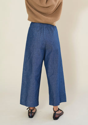 Back view of Poplinen Nin blue denim cropped wide leg pants with comfortable elastic waistband