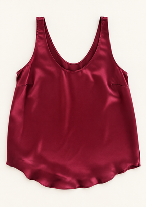A satin slip tank top in deep burgundy red, laid flat against a light cream background.